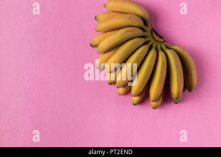 Style minimaliste. Arrière-plan de l'alimentation avec les fruits mûrs de la banane jaune sur du papier rose. Banque D'Images