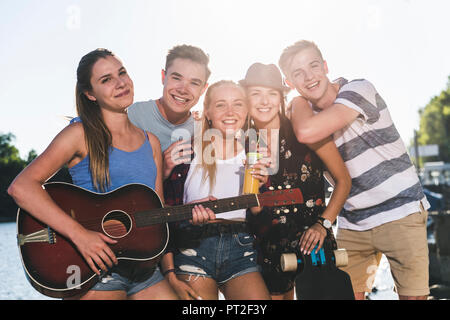 Portrait de groupe des amis heureux avec guitare du riverside Banque D'Images