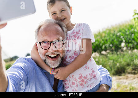 Homme mature et petite fille faisant l'amusement autoportraits dans le domaine Banque D'Images