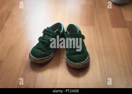 Portés et boueux paire de chaussures d'enfant sur un sol en bois d'une salle de séjour. Banque D'Images