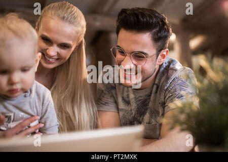 Heureux les jeunes parents à l'aide de tablet à la maison avec leur petite fille Banque D'Images