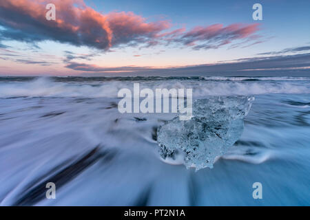 Petit bloc de glace sur la plage noire au coucher du soleil dans le lagon du Glacier Jökulsárlón, Austurland, l'Est de l'Islande, Islande, Europe Banque D'Images