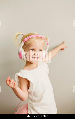 Portrait de petite fille blonde avec des écouteurs dancing Banque D'Images