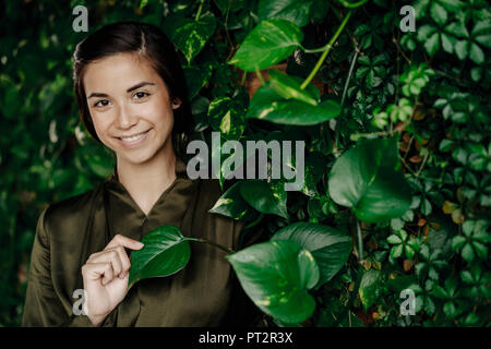 Le portrait de jeune femme au mur avec plantes grimpantes Banque D'Images