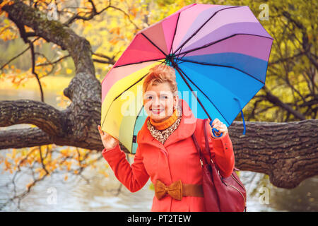 Femme blonde joyeuse avec un parapluie dans le parc de l'automne. Banque D'Images