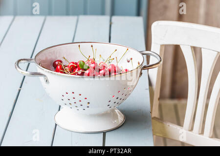 Les cerises dans une passoire sur table en bois Banque D'Images