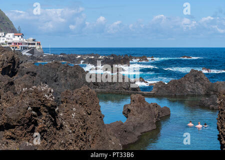 Trois hommes se baigner dans les piscines naturelles de Porto Moniz, Madeira, Portugal, région Banque D'Images