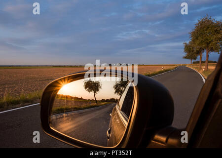 Coucher du soleil avec apple tree reflète dans tout miroir de voiture sur raod trip over Soester Börde, Haarstrang, Allemagne, Banque D'Images