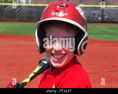 Young smiling Little League Baseball player holding bat avec son casque rouge. Banque D'Images