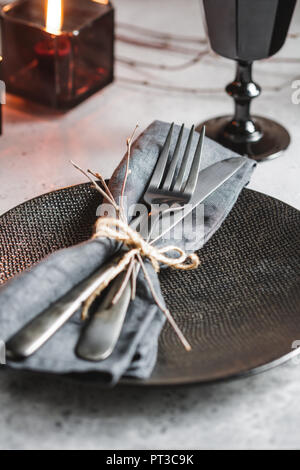 Table de fête dans un style noir chez les noirs des bougies sur un tableau blanc. Plaque avec fourchette et couteau sur une serviette en lin. Thanksgiving Halloween ou di Banque D'Images