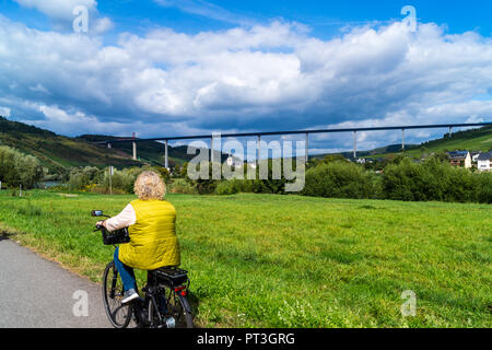 Un cycliste féminin à la recherche à l'Hochmoselübergang B50 pont de l'autoroute, en voie d'achèvement, piste cyclable Moselradweg, Zeltingen-Rcchtig, Mosel, Allemagne Banque D'Images