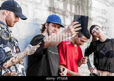 Groupe d'amis tatoués à l'aide de smart phone contre un mur gris sur un toit - Les jeunes personnes intoxiquées par mobile smartphone - Technologie millénaire conc Banque D'Images