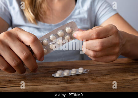 Close-up of a Woman's Hand Taking Medicine Plus de bureau en bois Banque D'Images