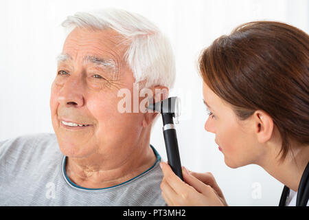 Close-up of a female Doctor Examining Senior Male Patient's Ear avec Otoscope Banque D'Images