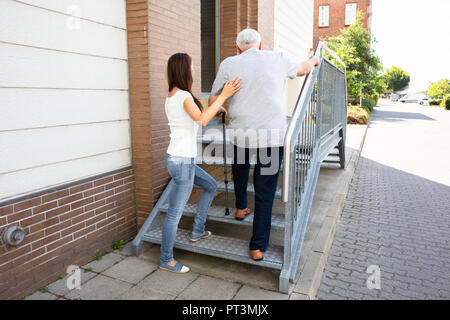 Vue arrière d'une jeune fille aidant son père principal escalier d'escalade Banque D'Images