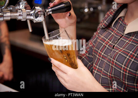 Le barman verse de bière à la pression dans le verre. Banque D'Images