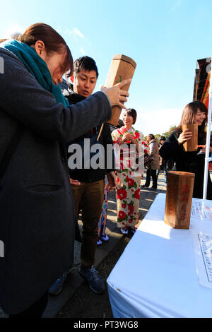 Man shaking omikuji cases avant de sortir le papier de fortune au temple shintoïste Yasaka à Kyoto au cours de leur première visite de la nouvelle année. Banque D'Images