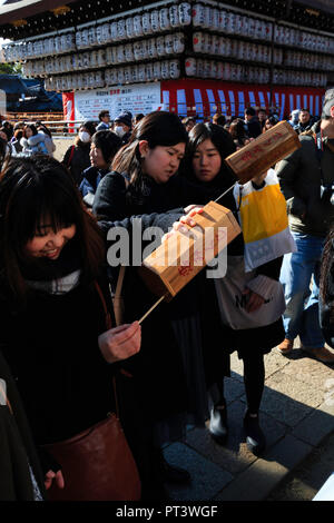 Les femmes agitant omikuji cases avant de retirer le papier de fortune au temple shintoïste Yasaka à Kyoto au cours de leur première visite de la nouvelle année. Banque D'Images
