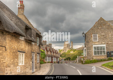 La lumière du soleil transperce les nuages lourds et éclaire la colline historique château de Corfe, dans le Dorset. Banque D'Images