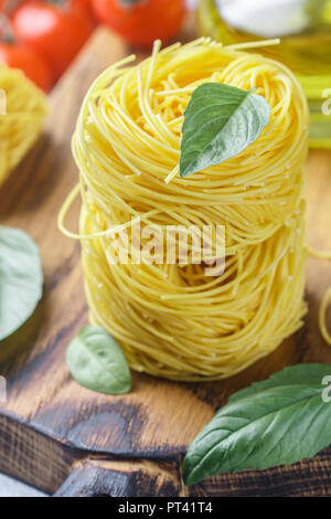 Pâtes aux Œufs crus nest - Homemade Capelli d'angelo, les cheveux d'ange. La cuisine italienne. Ingrédients pour un délicieux dîner. Le basilic, les vermicelles, tomates, olive Banque D'Images