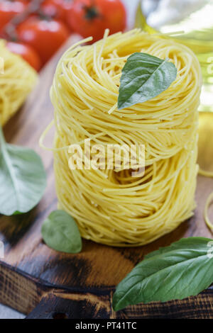 Pâtes aux Œufs crus nest - Homemade Capelli d'angelo, les cheveux d'ange. La cuisine italienne. Ingrédients pour un délicieux dîner. Le basilic, les vermicelles, tomates, olive Banque D'Images