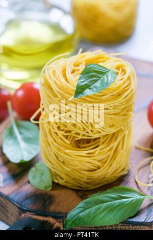 Pâtes aux Œufs crus nest - Homemade Capelli d'angelo, les cheveux d'ange. La cuisine italienne. Ingrédients pour un délicieux dîner. Le basilic, les vermicelles, tomates, olive Banque D'Images