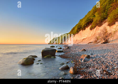 Allemagne, Mecklembourg-Poméranie-Occidentale, l'île de Rügen, Parc National de Jasmund, falaises de craie dans la lumière du matin, des rochers sur une plage de galets Banque D'Images