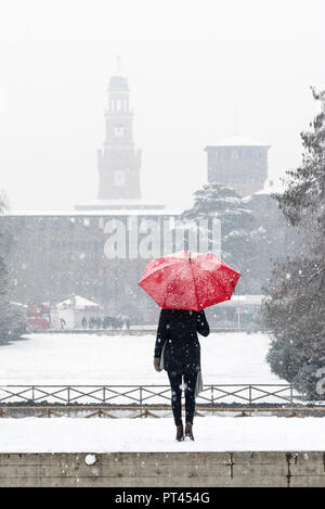 Une femme avec parapluie rouge admire la vue du parc Sempione pendant une chute de neige, Milan, Lombardie, Italie, Europe, Banque D'Images