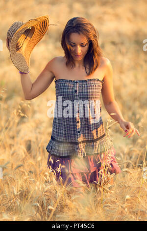 Femme brune en robe violette dans un champ de blé au coucher du soleil, Marches, Italie Banque D'Images