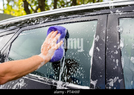 Automobile nettoyage en utilisant l'eau sous haute pression. L'homme lave sa voiture sous l'eau sous pression de service.lave-travailleur car.Protection de voiture concept.homme part avec éponge purpl lave-auto.focus sélectif. Banque D'Images