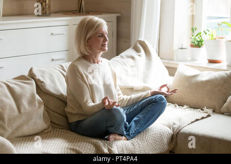 Santé l'esprit mature woman practicing yoga at home Banque D'Images