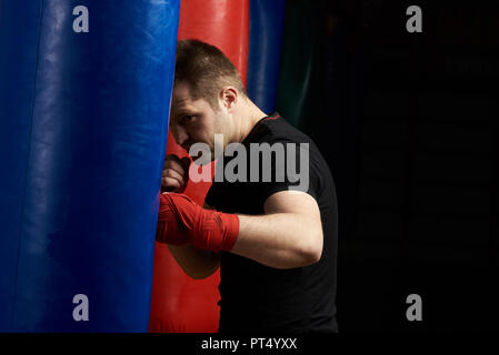 Thème de formation de boxe. Caucasian man coups de sac de boxe punch Banque D'Images