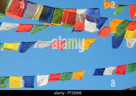 Drapeaux de prière bouddhiste tibétain voletant contre un ciel bleu à La Gacilly, Bretagne, France Banque D'Images