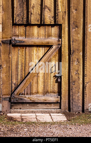 Une lourde porte en bois d'un vieux bâtiment - maison, grange, etc. La porte est verrouillée de l'extérieur avec un cadenas en métal argent plat sur une vis métallique. Le b Banque D'Images