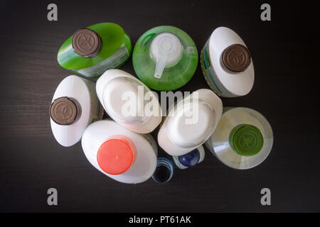 Un fond en bois noir avec divers produits de beauté corps et cheveux : shampooing, gel douche, crème hydratante, lotion pour les mains. Banque D'Images