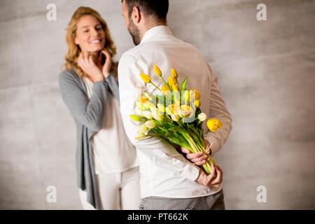 Voir à man giving bouquet de tulipes jaunes à sa petite amie Banque D'Images