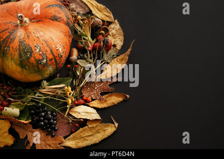 Citrouille dans les feuilles d'automne, couronne de baies, de noix, de glands, de fleurs,les herbes sur fond sombre, isolé. Meilleurs vœux. L'espace pour le texte. Heureux Thanksgiv Banque D'Images