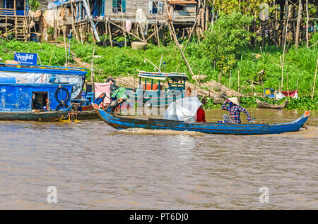 Siem Reap, Cambodge - 11 Avril 2018 : deux femmes aviron un bateau en bois à longue queue le long des rives du lac Tonle Sap en face d'un guindé village Banque D'Images