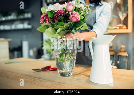 Fleuriste fleurs femelles en arrangement sur la table dans l'atelier. Artiste Floral bouquet décore sur le lieu de travail Banque D'Images