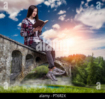 Femme assise sur arch pont de pierre et lit livre, paysage pittoresque sur l'arrière-plan. Communiquer des connaissances sur la nature paisible Banque D'Images