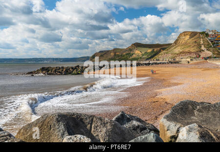 Par un après-midi ensoleillé sur la côte jurassique, une famille regarder les vagues casser sur la belle plage de West Bay, dans le Dorset. Banque D'Images