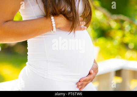 Close-up of pregnant woman standing piscine holding hands on belly Banque D'Images