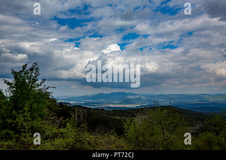 Beau paysage de printemps pris de Rhodopes, Bulgarie. Ciel nuageux à haut contraste avec les arbres en fleurs à l'avant Banque D'Images