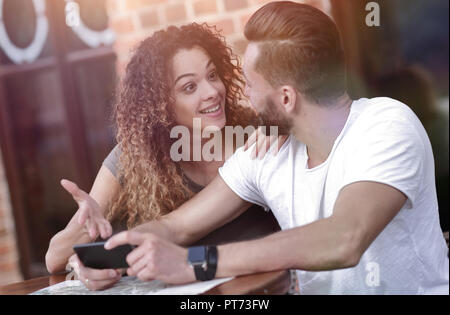 Couple heureux en utilisant un smartphone assis en terrasse Banque D'Images