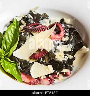 Les pâtes à l'encre de seiche noire, poulpes et le parmesan. Banque D'Images