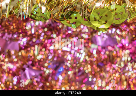 La texture de fond plein de bokeh violet avec des guirlandes d'or décoré par funny jack-o'-lantern pumpkin smiling faces décorations pour Halloween. Banque D'Images