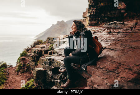 Femme assise sur la montagne et à la recherche à la vue. Female traveler détente sur rocky mountain. Banque D'Images
