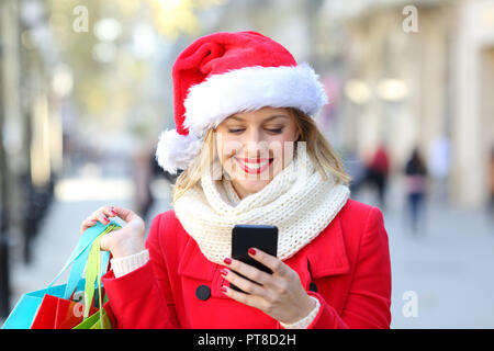 Happy shopper phone contenu sur Noël dans la rue Banque D'Images