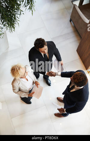 Portrait de graves affaires moderne en costumes se serrer la main tout en regardant fixement la collaboration, confiant la dame de papier du contrat Banque D'Images