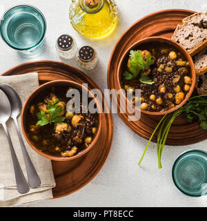 Noir marocain soupe de lentilles avec les pois chiches et le chou-fleur dans des bols sur la table. confort alimentaire végétalien sain avec du pain de blé entier Banque D'Images